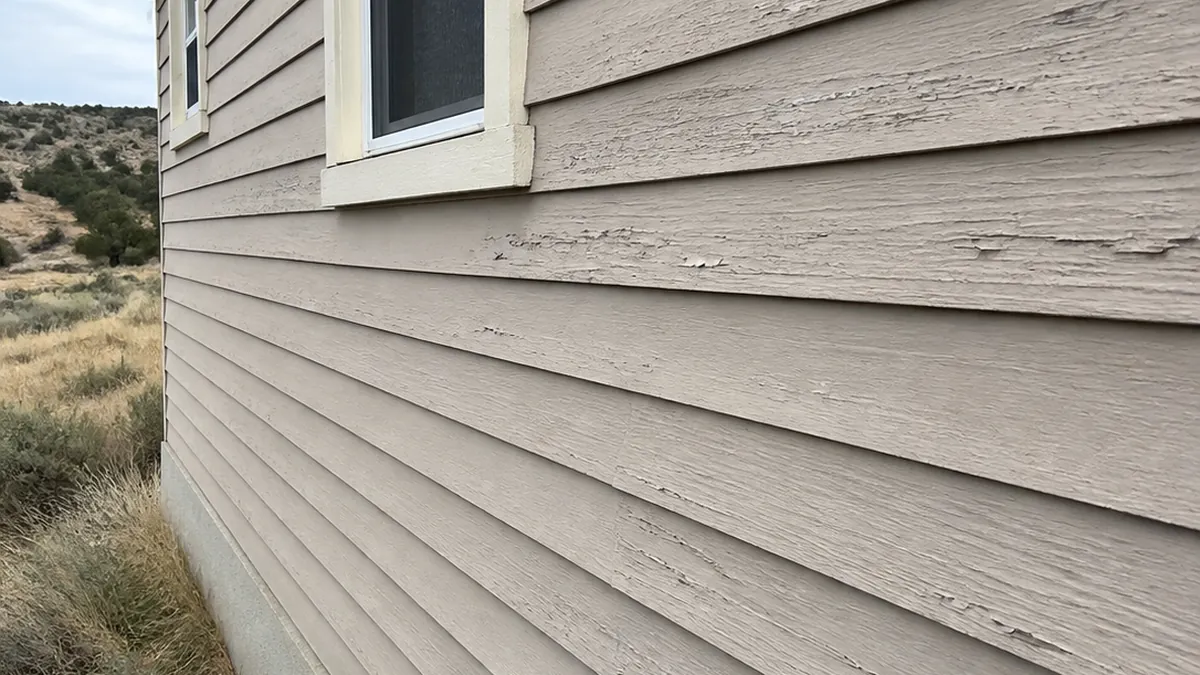Sun-faded exterior siding before a repaint in Reliance, Wyoming.